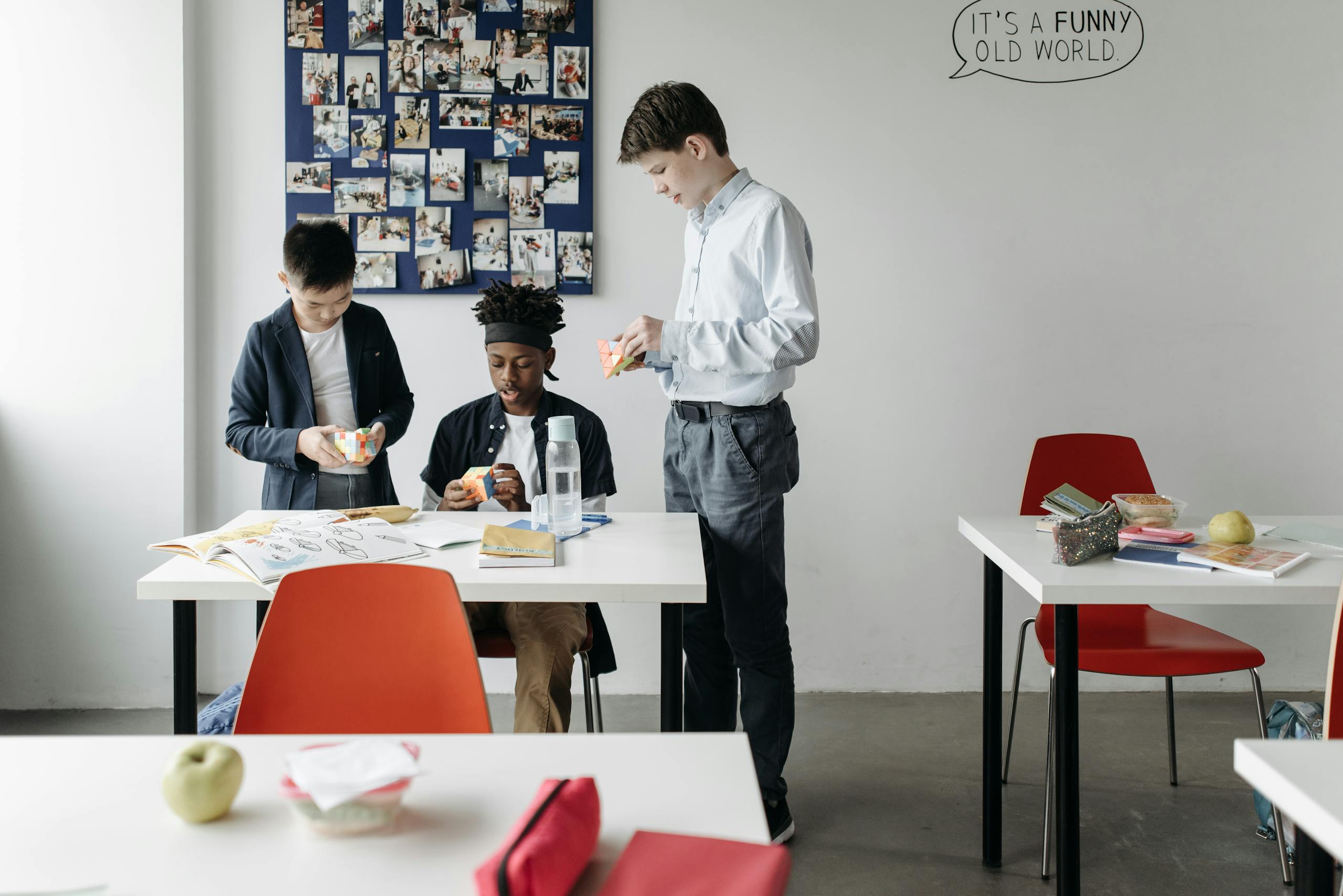 Three diverse students solving Rubik's Cubes in a classroom, fostering teamwork and learning.